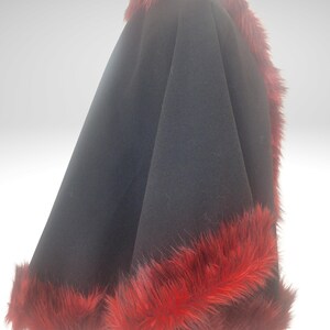 A side view of black alpaca short cape with red fur trim on a black mannequin