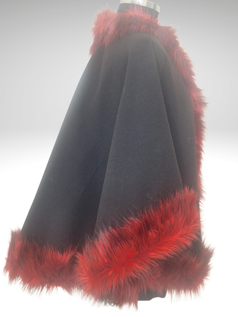 A side view of black alpaca short cape with red fur trim on a black mannequin