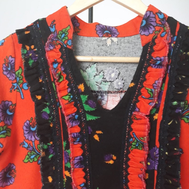 A red and black dress with a floral print and a ruffled neckline. The dress has a V-neck and is made of a lightweight fabric.