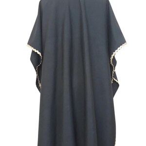 The back view of a black linen garment with gold trim, displayed on a mannequin.