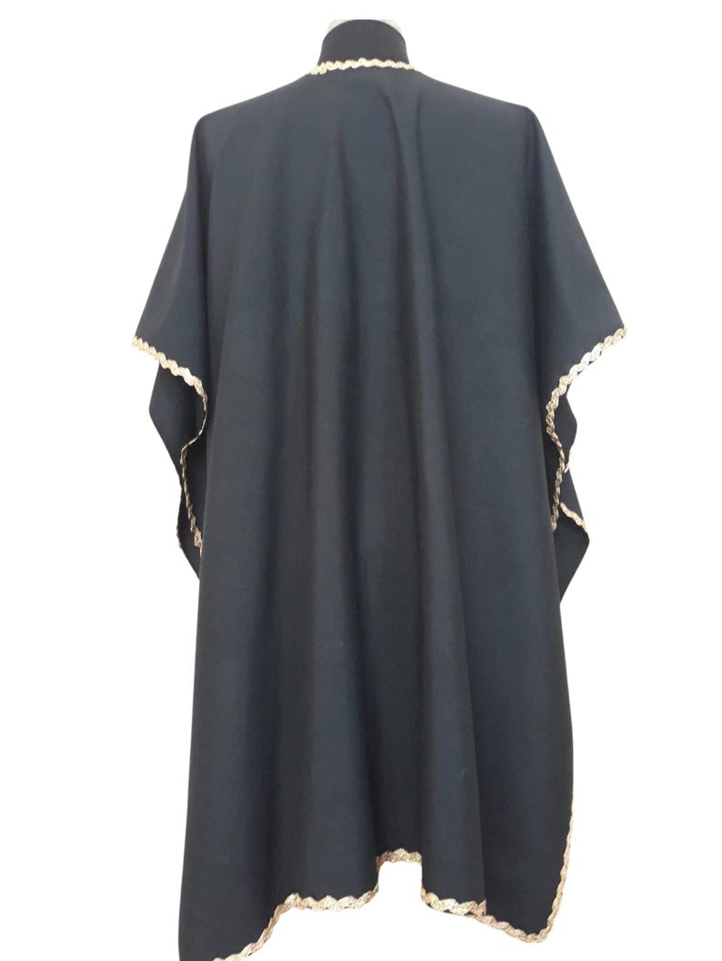 The back view of a black linen garment with gold trim, displayed on a mannequin.
