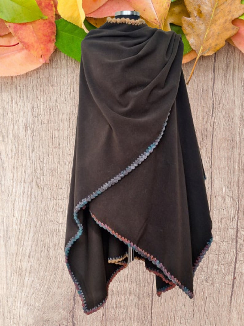 Reversible Large Cape, shawl,  poncho with a multicolored crocheted trim. The poncho is displayed on a mannequin wrap style