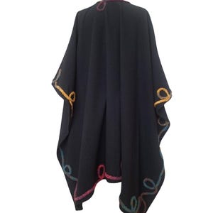 A back view of vintage inspired  handmade cashmere long ruana wrap,  plus size cape poncho, decorated with colorful rainbow Romanian cord, photographed in natural outdoor light.