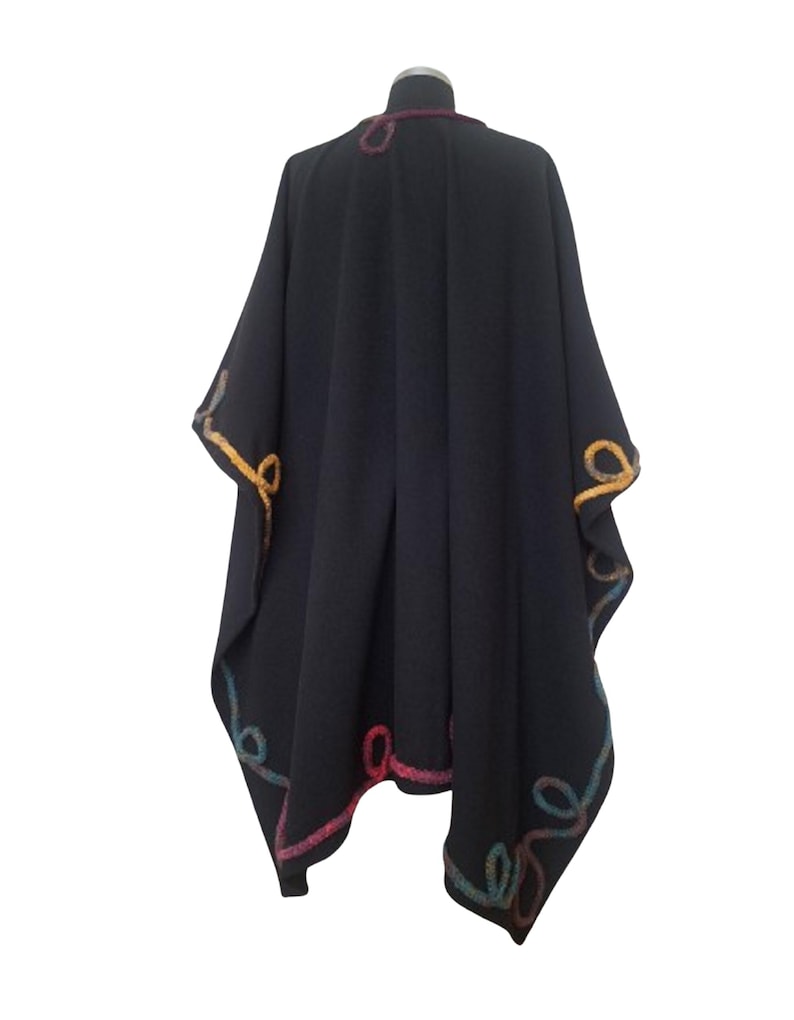 A back view of vintage inspired  handmade cashmere long ruana wrap,  plus size cape poncho, decorated with colorful rainbow Romanian cord, photographed in natural outdoor light.