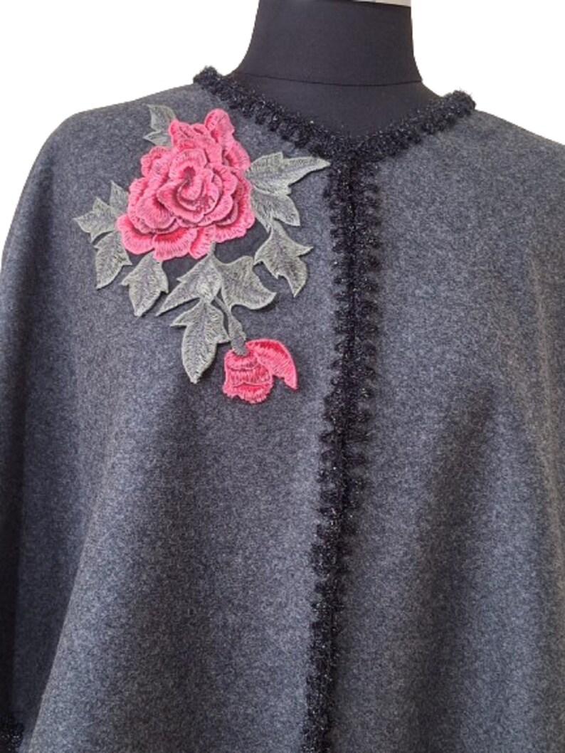 May include: Gray wool poncho with a black crocheted trim and a pink embroidered rose.