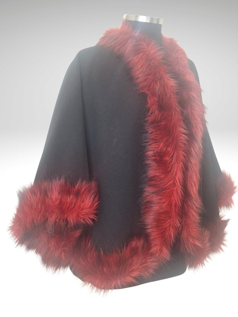 A Right  view of black alpaca short cape with red fur trim on a black mannequin
