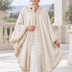 the model showcasing Front view of a luxury Ivory Bridal Cashmere Coat, Jacket with Lavish Trim, Couture Evening Cape, featuring a seamless circular cut, elegant drape, and one-size oversized silhouette.
