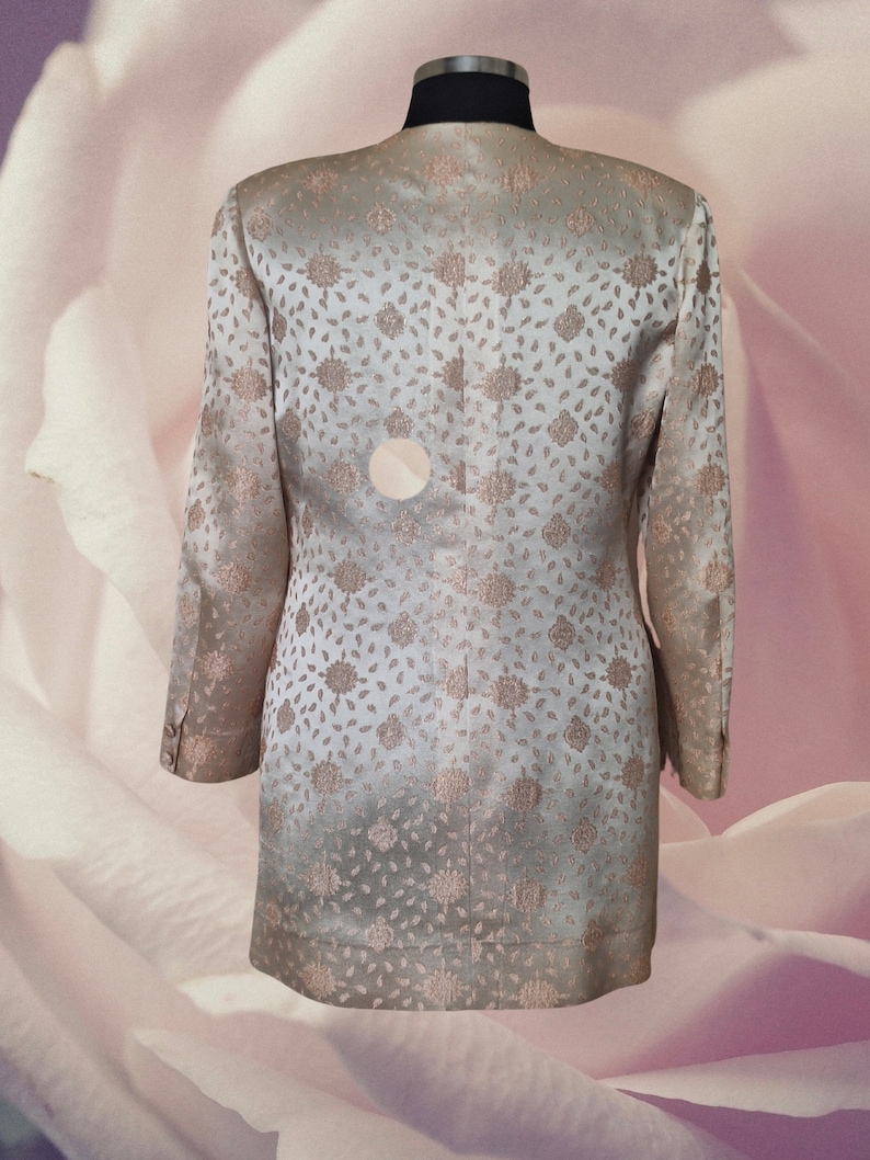 May include: A light beige blazer with a floral pattern. The blazer has a long sleeve and a button closure.
