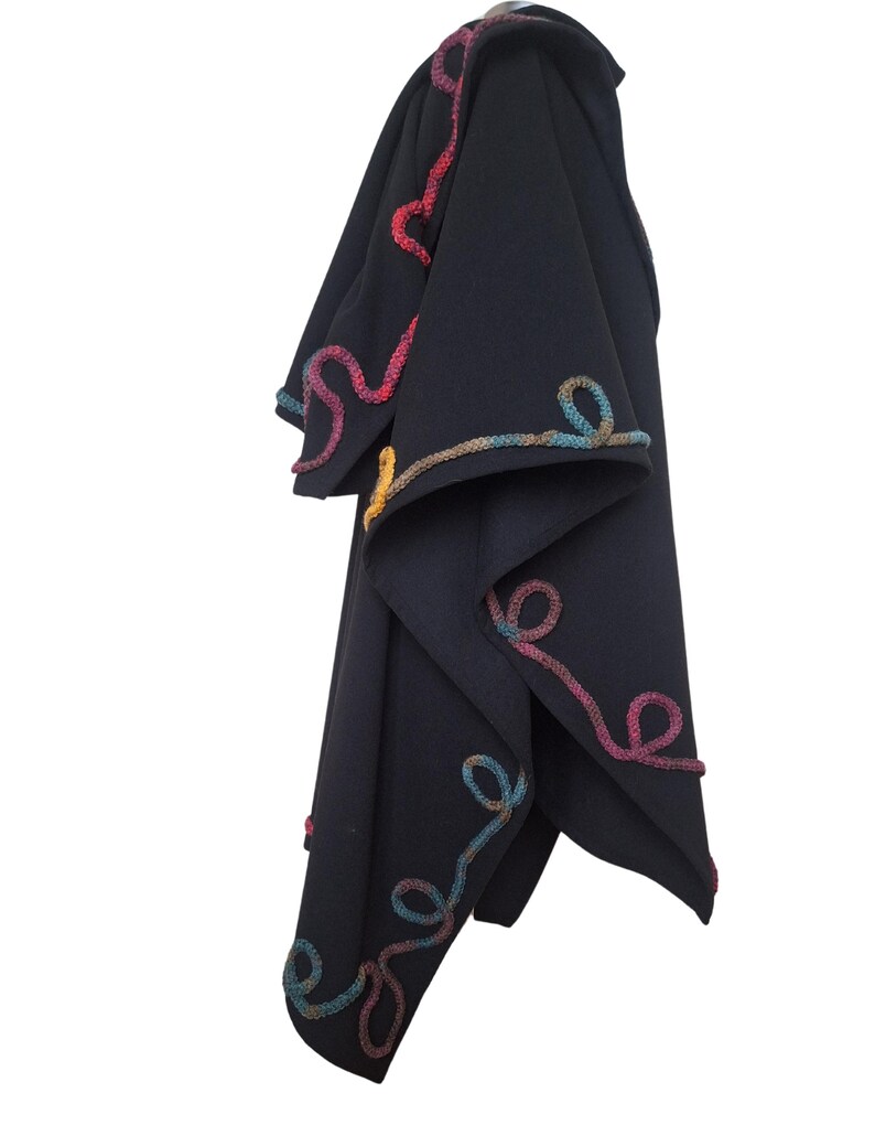 A side view of Elegant handmade cashmere Ruana wrap, vintage inspired plus size cape poncho, decorated with colorful rainbow Romanian cord embroidery, photographed in natural outdoor light.