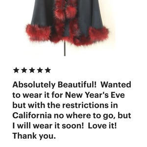 A black faux fur cape with a red faux fur trim and a pom-pom detail.  "Absolutely Beautiful! Wanted to wear it for New Year's Eve but with the restrictions in California no where to go, but I will wear it soon! Love it! Thank you. Verified Etsy Buyer"