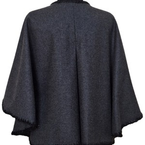 May include: A charcoal gray wool poncho with a black beaded trim around the neckline and edges.