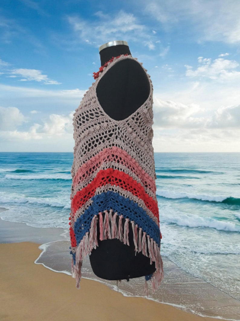 May include: A handmade crochet top in a variety of colors, including beige, pink, red, and blue. The top features a fringed hemline and is displayed on a black mannequin. The crochet design has a textured, open weave.