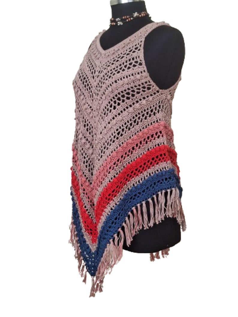 May include: A sleeveless, open-weave crochet top in a dusty rose color. The top features a V-neck and a diagonal color block design with stripes of pink, red, and blue. The bottom edge has a fringe detail.