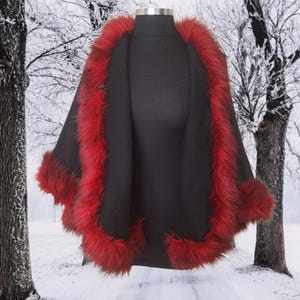 A inside  view of the Alpaca short cape with red fur trim on a black mannequin in a snowy forest