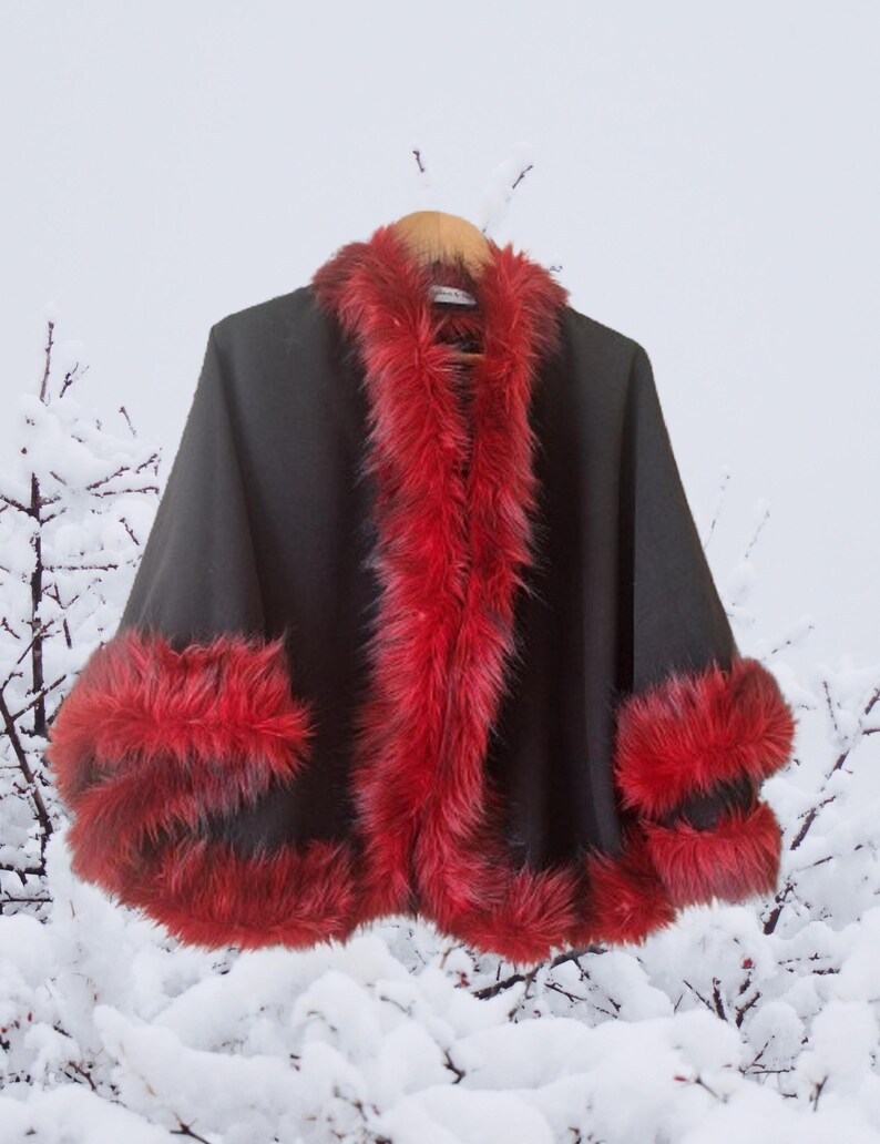 “Elegant black alpaca half cape with luxurious red vegan fur trim, photographed in a natural lighting. The rich contrast of red and black creates a striking, festive look perfect for cold days. Designed by HandmadeByNadya — timeless elegance in motion.”
