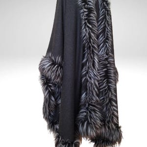 May include: A dark grey cape with faux fur trim. The cape has a high collar and is trimmed with black, white, and grey faux fur along the edges and around the sleeves. The cape is displayed against a white background.