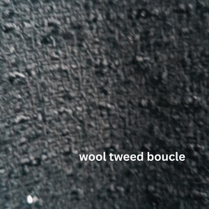 Close-up view of a black wool tweed boucle fabric. The texture is thick and nubby with a slightly irregular surface. The image includes the text 'wool tweed boucle' in white sans-serif font.