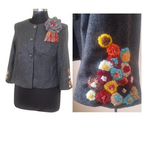 May include: A gray wool jacket with colorful embroidered flowers on the sleeves and a decorative brooch on the front.
