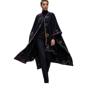 A live  fashion model wearing cashmere long cape poncho with colorful artisan handmade cord embellishments along the edges