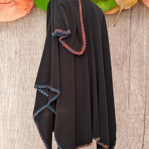 Alpaca Reversible ruana  with a multi-colored crocheted trim. The cape is displayed on a mannequin throwed one sides over the shoulder for a more romantic or dramatic wrap.