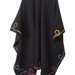 Luxurious cashmere wool cape handcrafted with artistic embellishments and an elegant draped silhouette. A timeless plus size statement piece for winter layering. The garment is shown on a hanger against a white background