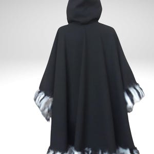 May include: A black hooded cape with faux fur trim. The cape features a wide, flowing design and a hood. The trim is a mix of black, white, and gray, adding a decorative element to the garment. The cape is made of a soft, draping fabric.