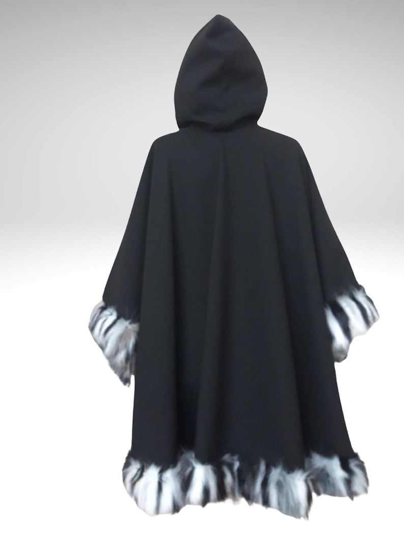 May include: A black hooded cape with faux fur trim. The cape features a wide, flowing design and a hood. The trim is a mix of black, white, and gray, adding a decorative element to the garment. The cape is made of a soft, draping fabric.
