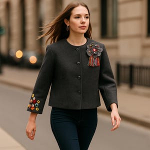"Artisan handmade wool and alpaca cropped jacket, featuring vibrant hand-embroidered floral details on the sleeves and a unique handcrafted brooch – a one-of-a-kind design celebrating craftsmanship and color."