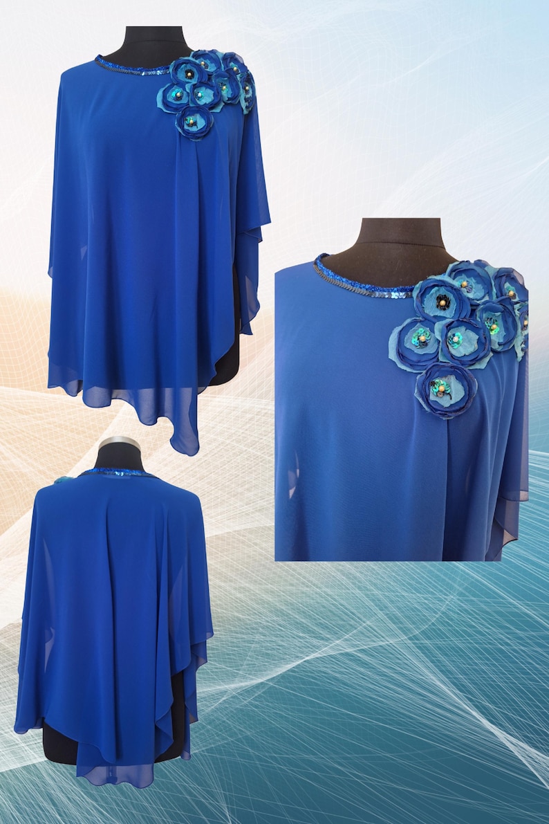 May include: A royal blue cape-style top with a round neckline and floral embellishments. The top features a flowing, asymmetrical design with layered sleeves. The neckline is adorned with sequins, and the shoulder has a cluster of fabric flowers.