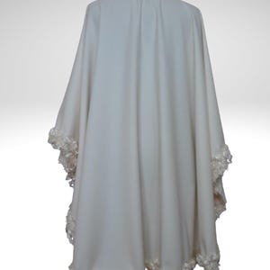 Back view of an off-white cashmere bridal cape with luxurious textured trim outlining the hem and neckline. Lightweight, flowing winter wedding shawl with a timeless vintage-inspired design.”