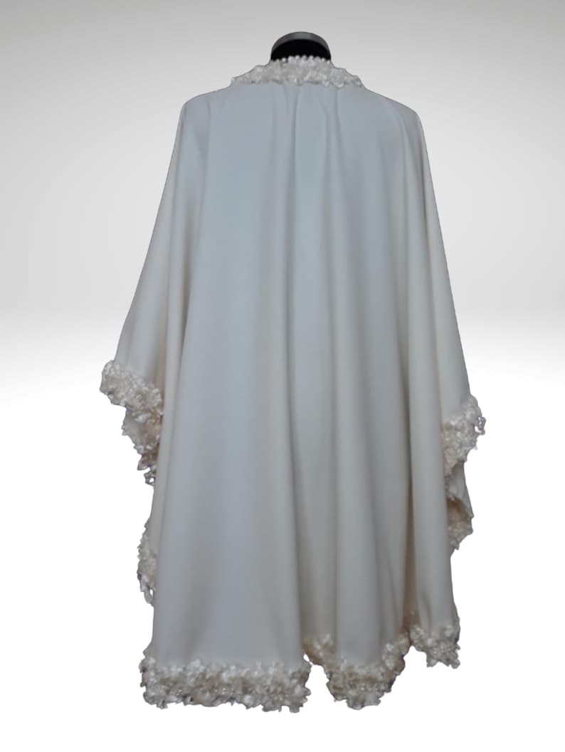 Back view of an off-white cashmere bridal cape with luxurious textured trim outlining the hem and neckline. Lightweight, flowing winter wedding shawl with a timeless vintage-inspired design.”