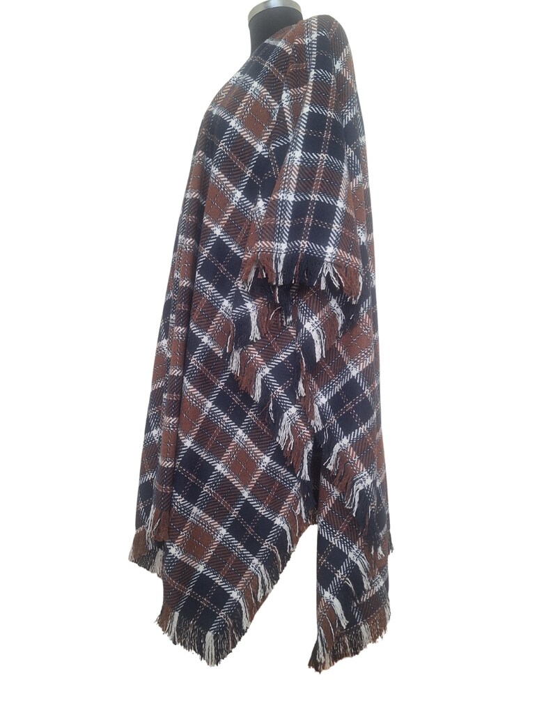 K&ouml;nnte beinhalten: Ein braunes, schwarzes und wei&szlig;es kariertes Poncho mit Fransenbesatz.