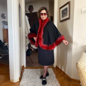 Black and red alpaca wool cape, full-circle cut with voluminous fur trim — designed to move gracefully and bring color to cold winter days