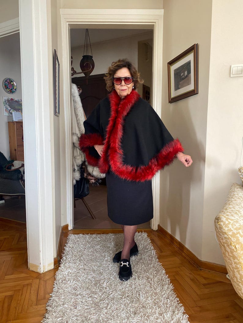 Black and red alpaca wool cape, full-circle cut with voluminous fur trim — designed to move gracefully and bring color to cold winter days