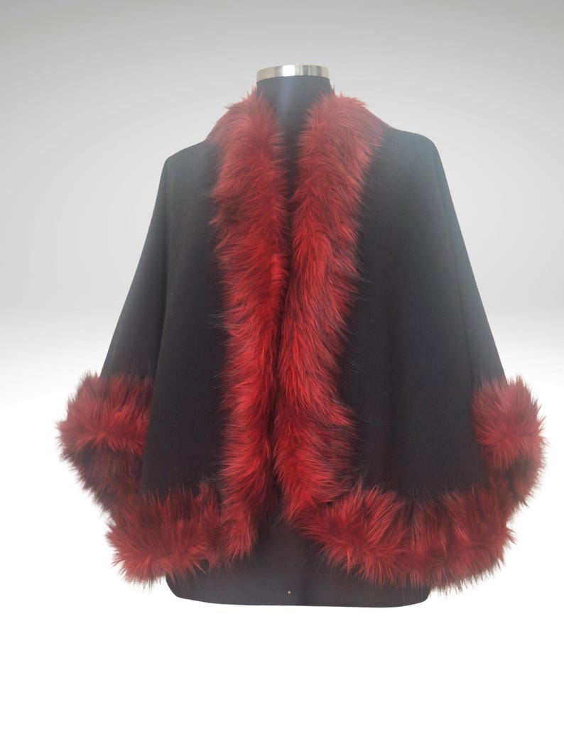 “Elegant black alpaca and wool half cape with luxurious red vegan fur trim, photographed in a natural lighting. The rich contrast of red and black creates a striking, festive look perfect for cold days. Designed by HandmadeByNadya — timeless elegance in motion.”