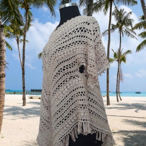 Boho crochet poncho dress with flowing sleeves, handmade from breathable cotton, worn as a swimsuit cover up at the beach.