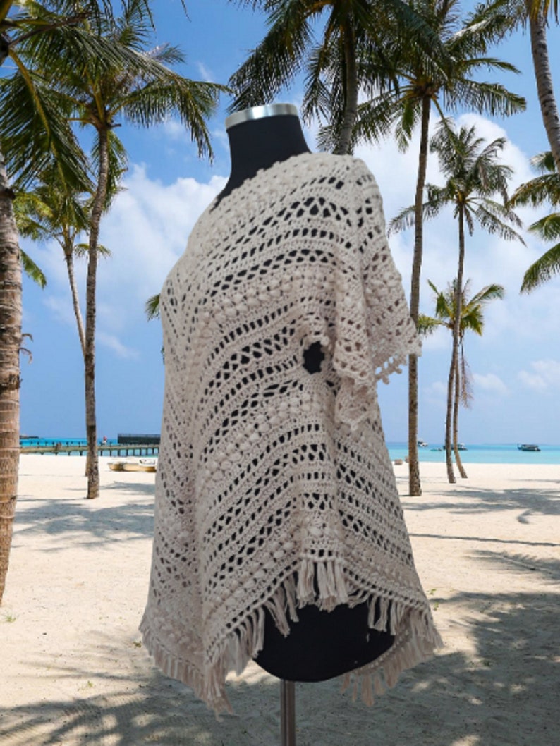 Boho crochet poncho dress with flowing sleeves, handmade from breathable cotton, worn as a swimsuit cover up at the beach.