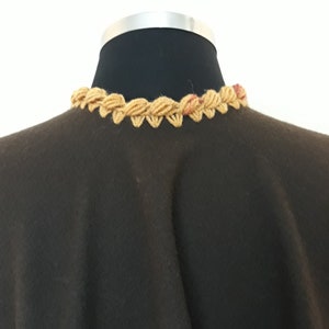 Close-up view of neck collar. colorful handmade crochet trim on luxurious baby alpaca ruana showcasing artisan craftsmanship.