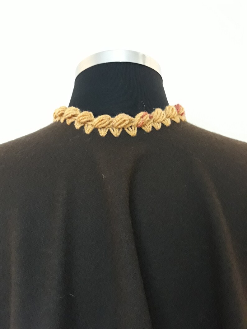 Close-up view of neck collar. colorful handmade crochet trim on luxurious baby alpaca ruana showcasing artisan craftsmanship.