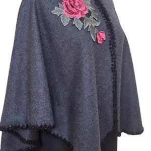 May include: Gray poncho with a black trim and a pink embroidered rose.