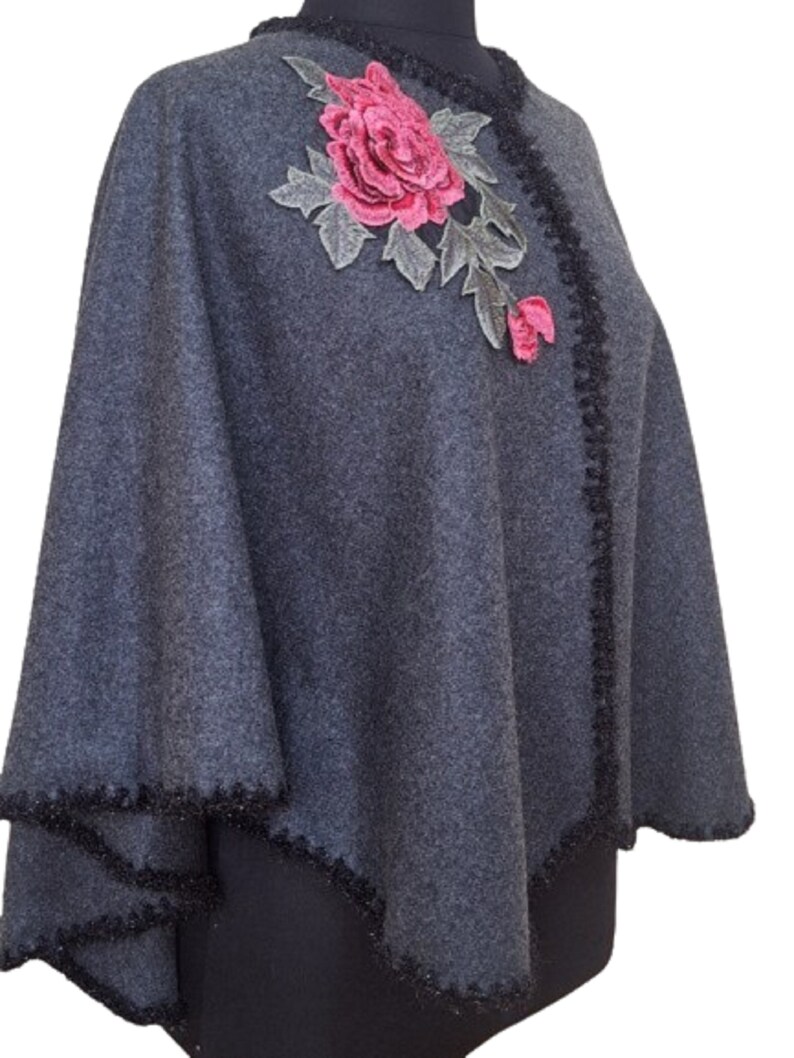 May include: Gray poncho with a black trim and a pink embroidered rose.