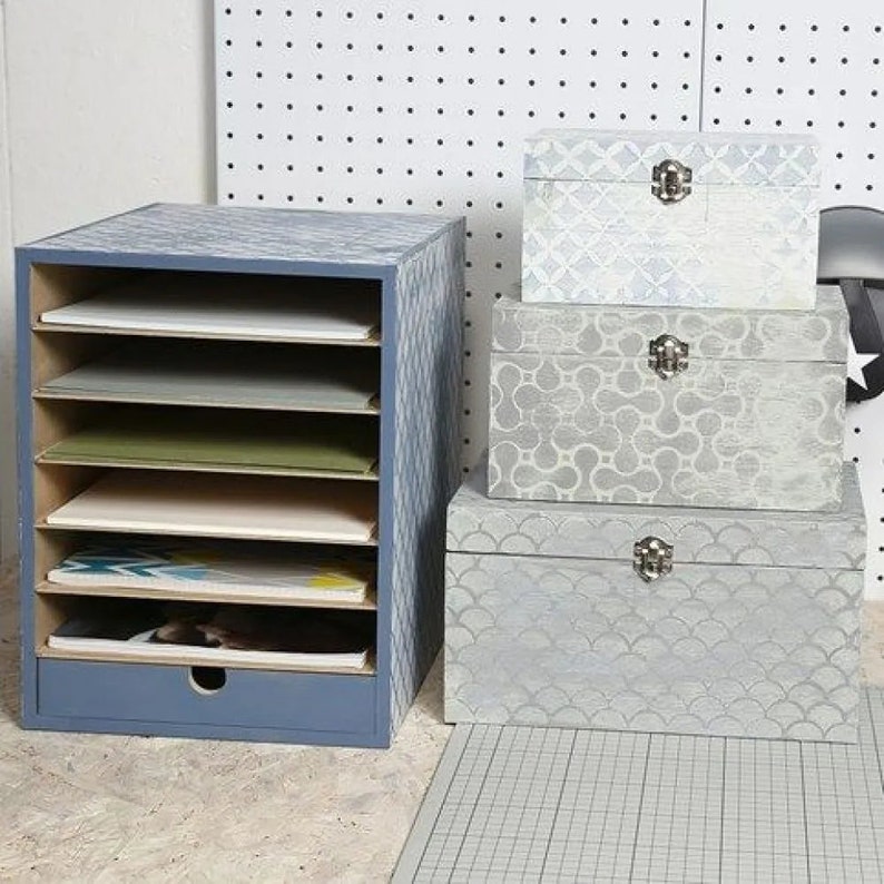 May include: A blue file organizer with six shelves and a drawer. Three decorative boxes with different patterns are stacked on top of the organizer. The boxes are all painted in shades of gray and white.