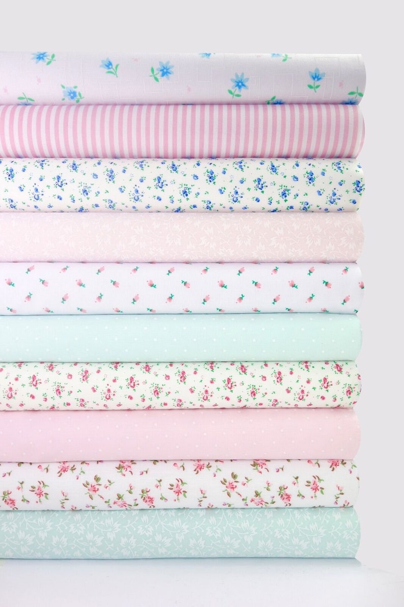 May include: A stack of 10 fabric rolls with various floral patterns in shades of pink, white, and light blue.