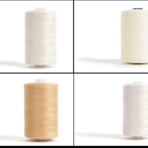 May include: Four spools of thread, two white, one beige, and one cream.