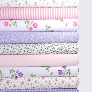 May include: A stack of 10 fabric rolls with various floral patterns in shades of pink, purple, and white. The fabrics feature small floral prints, stripes, polka dots, and gingham.