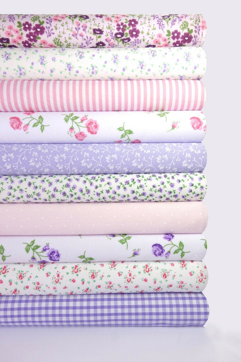 May include: A stack of 10 fabric rolls with various floral patterns in shades of pink, purple, and white. The fabrics feature small floral prints, stripes, polka dots, and gingham.