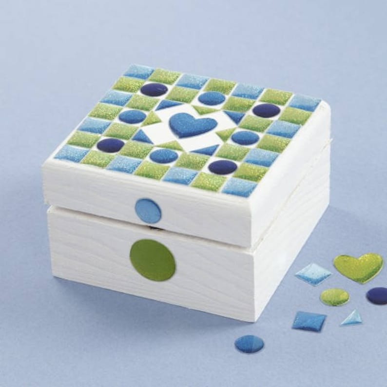May include: A white wooden box with a mosaic design on the lid. The mosaic is made of blue, green, and white tiles. The box has a heart-shaped design in the center of the lid. The box is surrounded by small blue, green, and white tiles.