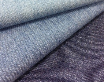 Op de afbeelding: Twee stukken denim stof, een lichtblauw en een donkerblauw, zijn op elkaar gevouwen. De stof heeft een textuur.