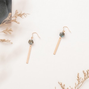 May include: A pair of gold dangle earrings with a dark green and blue gemstone pendant on each earring.
