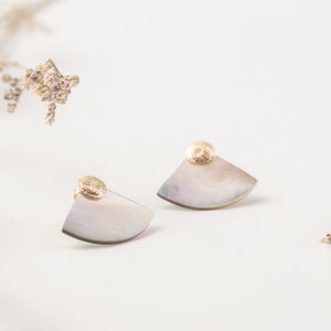 May include: A pair of gold and iridescent shell earrings. Each earring features a small, textured gold disc at the top and a half-circle shell shape.